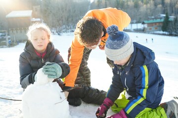 Children Building a Snowman on a Sunny Winter Day