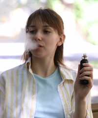 Young woman using electronic smoking device outdoors
