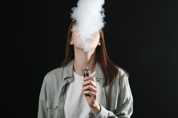Woman using electronic smoking device on black background