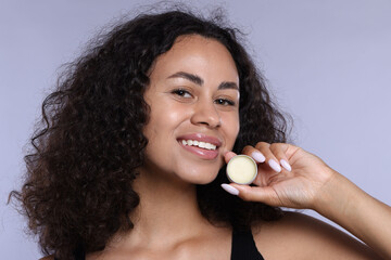 Smiling woman with lip balm on grey background, closeup