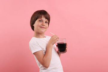 Cute little boy with glass of refreshing soda drink on pink background