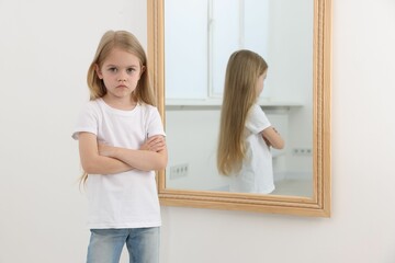 Upset little girl near mirror at home