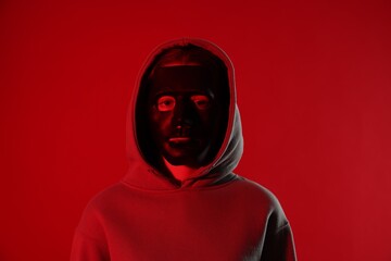 Anonymity. Woman wearing mask on red background