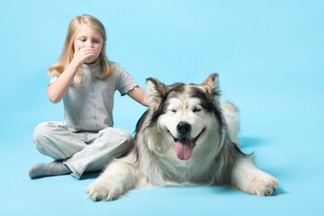 Girl suffering from allergy with her dog on light blue background