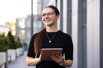 Successful businesswoman with tablet near office building