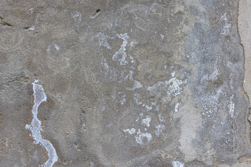Rough textured concrete outdoor wall with cracks and discoloration