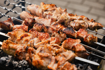 Juicy grilled meat skewers placed on barbecue grill, showcasing smoky aroma and sizzling texture in an outdoor cooking environment