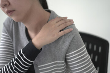 Tired asian business woman massaging rubbing stiff sore neck and back tensed muscles fatigued from...