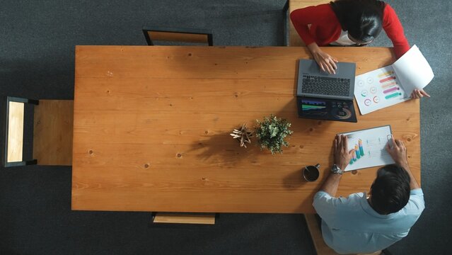 Top view of skilled business man and project manager sitting at meeting table. Smart business woman open laptop and start working while working together with colleague at meeting room. Convocation.