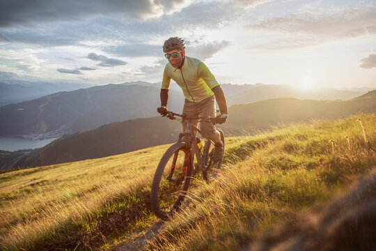 Cross Country Mountain Biker on Scenic Alpine Trail at Sunset