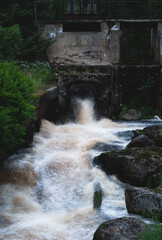 A flowing river through an old dam on an overcast day in Scandinavia. 