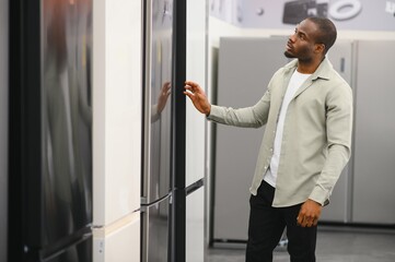 Customer choosing refrigerator in electronics store appliance section