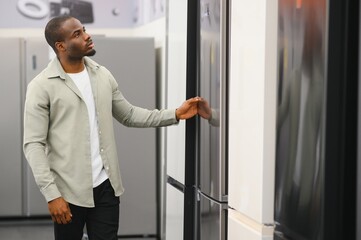 Customer choosing refrigerator in electronics store appliance shop