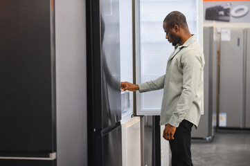 Customer choosing refrigerator in electronics store appliance shop