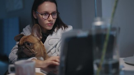 Woman working at home with laptop accompanied by her French bulldog dog pet
