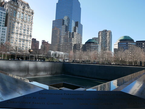New York, NY, USA - February 2, 2024: 9/11 Memorial with the reflecting pool and engraved names honoring victims, surrounded by modern skyscrapers at the former World Trade Center site.