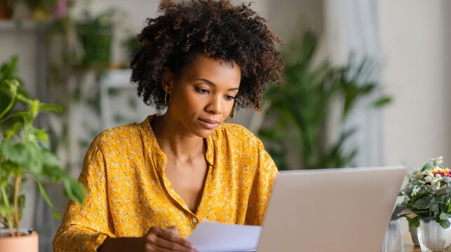 Serene home office where Black woman reviews profit‑and‑loss financial report, enters bookkeeping data on laptop, and drafts audit plans for efficient asset management and tax compliance