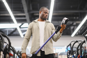 Customer carefully choosing vacuum cleaner in electronics store