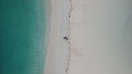 drone shot of a couple sitting by the beach