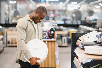 Customer choosing robotic vacuum cleaner in electronics store