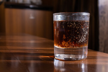 Glass of fizzy drink on wooden table in a dimly lit venue