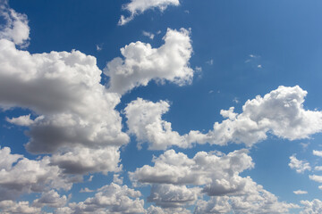 Bright clouds drift across a clear blue sky during midday