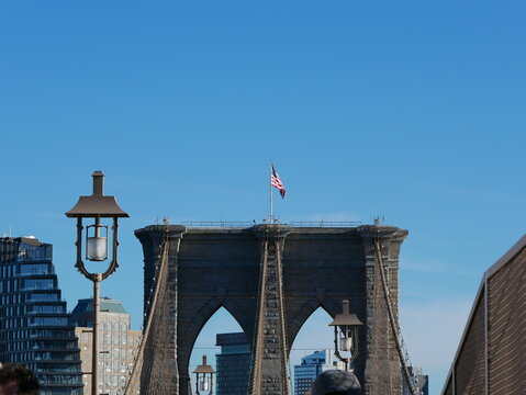 Front view of one of the iconic stone towers of the Brooklyn Bridge in New York City, with steel cables converging symmetrically under a clear sky.