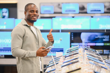 Customer giving thumbs up while choosing smartphone in electronics store