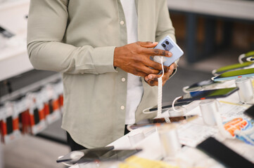 Customer holding smartphone in electronics store, shopping for mobile devices