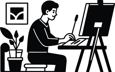A man sits at a desk, working on a computer with an easel and plant nearby