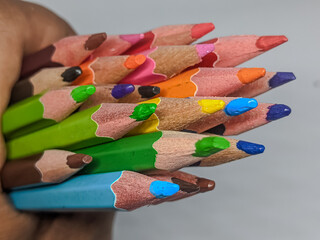 A vibrant cluster of colored pencils held, highlighting sharpened tips and wood texture. Symbolizes...