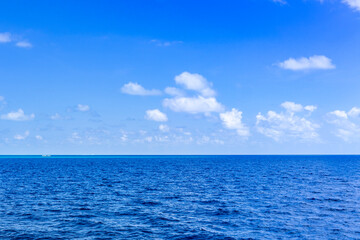 Landscape of beautiful summer sparkling sea water contrasts with bright blue sky and clear white clouds. Space for free texts.
