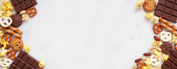 Sweet and salty snacks double border over a white marble banner background. Chocolate, popcorn,...
