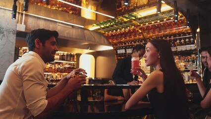 Couple making a toast with cocktail paloma and old fashioned at luxurious bar in lively conversation drinks celebrating a special party at vibrant nightclub while friend drinking Margarita. Vinosity.