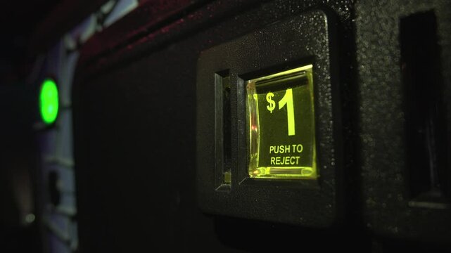 Canadian dollar coin inserted into arcade pinball machine.