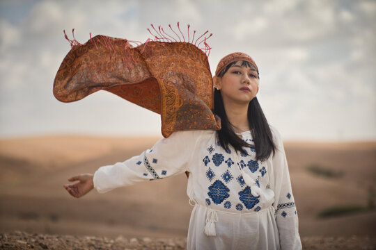 woman in traditional clothes with shawl in desert