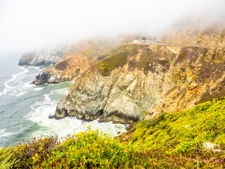 Fog rolling over cliffs and tunnel at Devils Slide, California coast