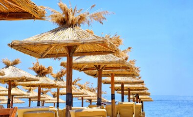 Straw beach umbrellas on the beach. Seaside vacation concept.