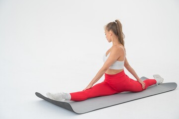 Young woman doing splits exercises on white background.