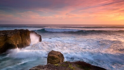 serene coastal sunset landscape with rocky formation turbulent ocean waves and pastel sky