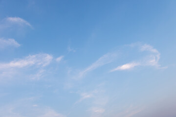 Serene blue sky with soft clouds creates a calm, natural background for design and artistic...