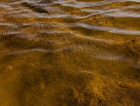 A close up view of murky water with visible ripples and a glimpse of the riverbed underneath the surface - Powered by Adobe
