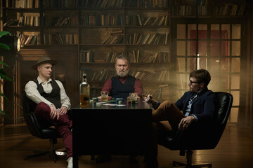 Three distinguished gentlemen playing poker game in a vintage old library