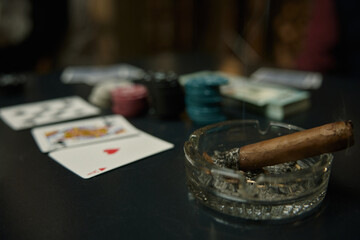 A tranquil poker scene featuring an extinguished cigarette, colorful chips, and playing cards on