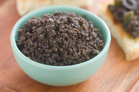 Homemade french black olive tapenade spread served in a small bowl (Selective Focus, Focus one third into the spread) 