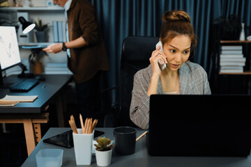 Businesswoman calling with customers to make new project job at modern office while coworker checking paperwork folder of business plan to database report meeting at over late night time. Infobahn.