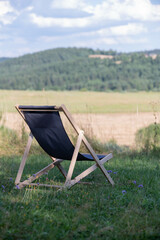 chair on grass with hills and clouds in background 