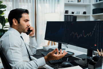 Trader businessman calling to consultant or partner with two stock exchange investment, compare...