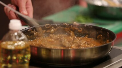 Close-up of a chef stirring a savory, steaming dish in a hot pan over a stove. This dynamic shot captures the essence of food preparation, culinary expertise, and the creation of a delicious meal.