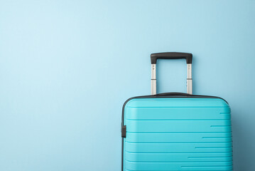 A blue hard-shell suitcase positioned in front of a light blue backdrop, evoking travel plans